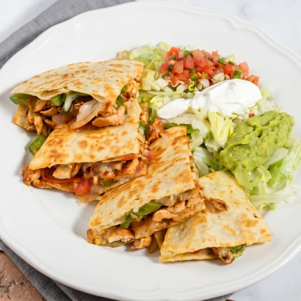 Chicken quesadillas with bell peppers and onions, served with guacamole, sour cream, and pico de gallo.