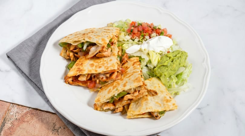 Chicken quesadillas with bell peppers and onions, served with guacamole, sour cream, and pico de gallo.