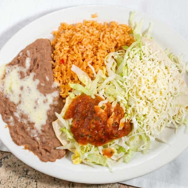 A white plate with refried beans, rice, shredded lettuce, salsa, and a cheese-covered tortilla.