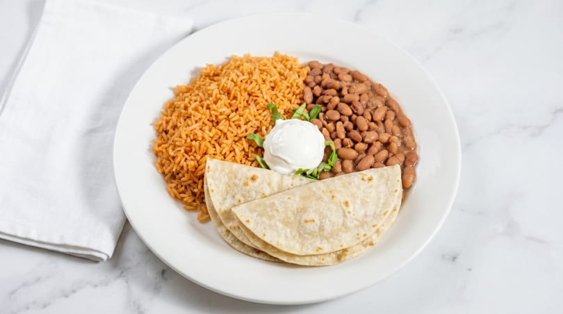 Mexican rice, pinto beans, flour tortillas, and a dollop of sour cream with cilantro.